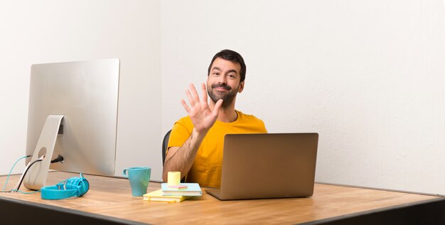 Homme travaillant avec laptot dans un bureau comptant cinq avec les doigts