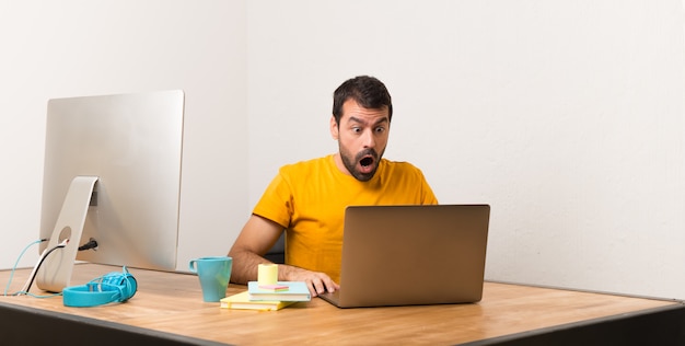 Homme travaillant avec laptot dans un bureau avec une expression faciale surprise et choquée