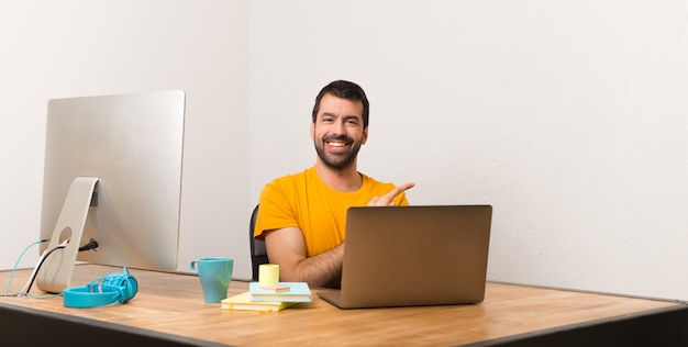 Homme travaillant avec laptot dans un bureau pointant sur le côté pour présenter un produit