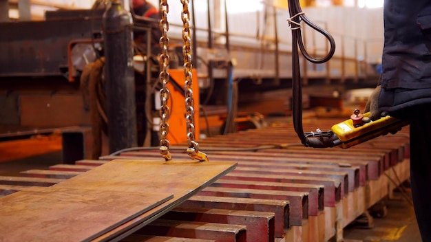 Un homme travaillant avec une machine de levage sur l'usine tenant un panneau de commande