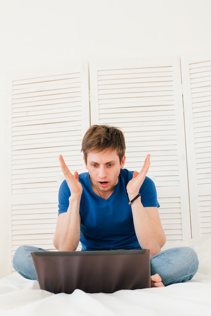 Homme travaillant sur un ordinateur portable assis sur le lit