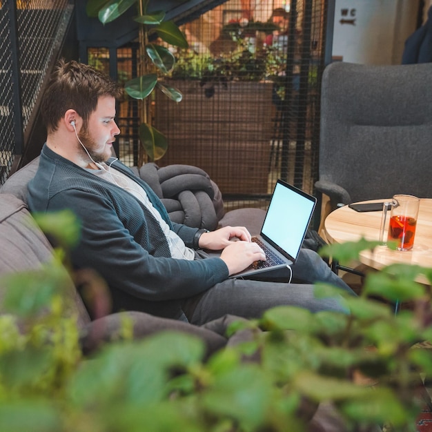 homme travaillant sur un ordinateur portable dans un café écoutant de la musique avec un casque espace de copie d'écran blanc