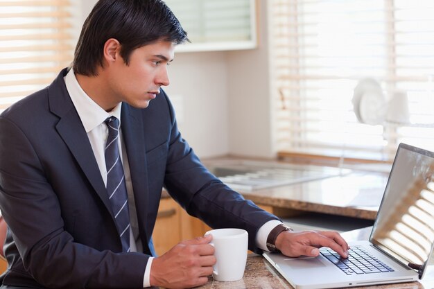 Homme travaillant avec un ordinateur portable tout en buvant du café