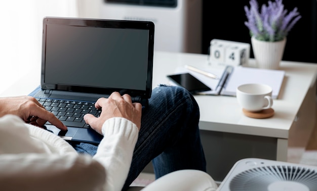 Homme travaillant avec un ordinateur portable tout en étant assis dans le salon à la maison, travaillant à domicile concept.