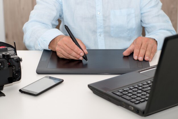Homme travaillant sur sa tablette graphique, gros plan des mains