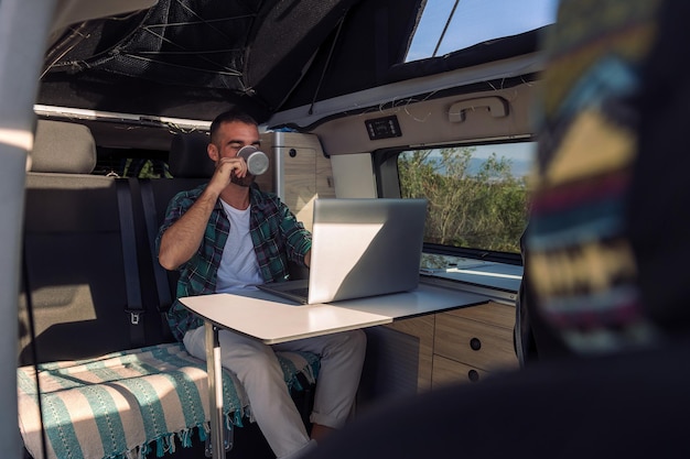 Homme travaillant sur son ordinateur portable depuis son camping-car