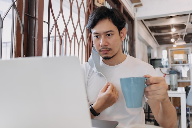 L'homme travaille au café avec un masque sur le visage concept de freelance avec covid