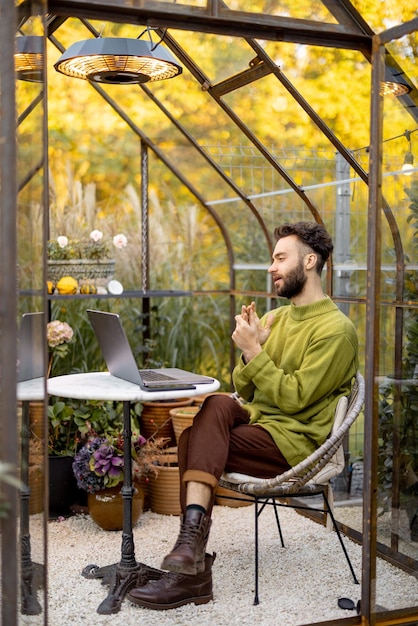 L'homme travaille à distance sur un ordinateur portable dans le jardin
