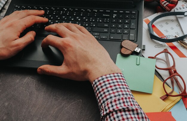 Un homme travaille à la maison ou au bureau sur un ordinateur, ses mains en tapant du texte