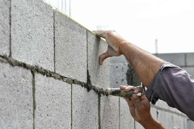 Un homme travaille sur un mur de blocs.