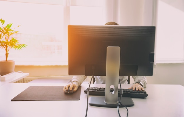 L'homme travaille avec un ordinateur au bureau