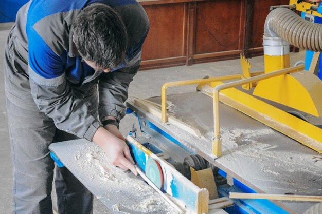 Un homme travaille sur un projet de menuiserie en utilisant une scie pour couper un morceau de bois