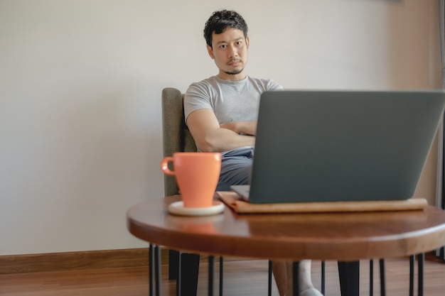 L'homme travaille avec son ordinateur portable et boit du café.