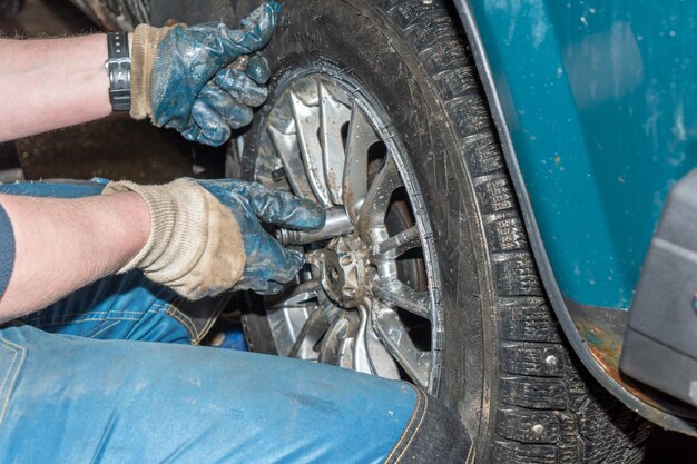 Un homme travaille sur une voiture avec une clé.