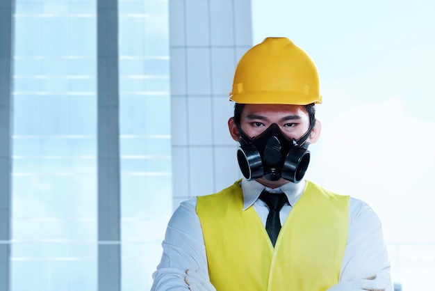 Photo homme travailleur asiatique avec un masque de protection et un casque jaune debout