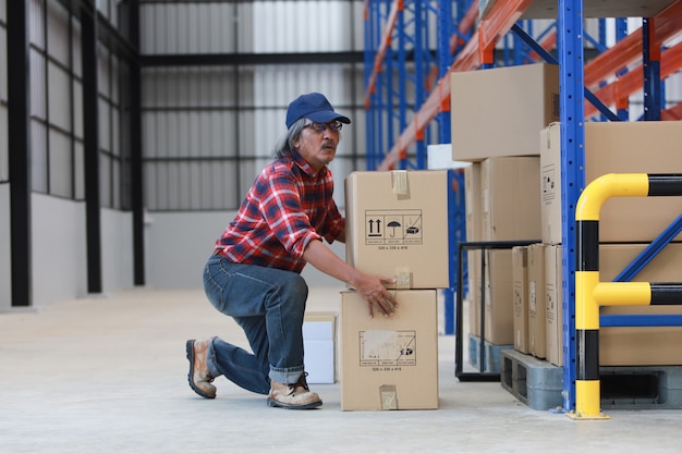 Homme travailleur asiatique soulever une boîte lourde en usine