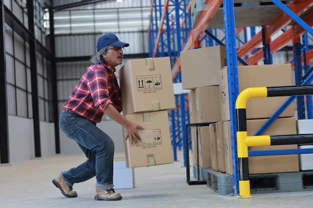 Homme travailleur asiatique soulever une boîte lourde en usine