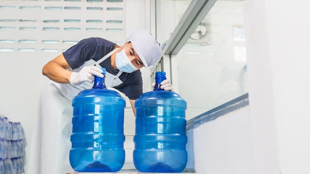 Homme travailleur en vêtements de travail et avec un masque de protection sur son visage travaillant dans une usine d'eau potable