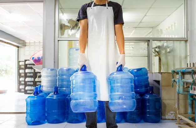 Homme travailleur en vêtements de travail travaillant dans une usine d'eau potable vérifiant les gallons d'eau bleue avant expédition