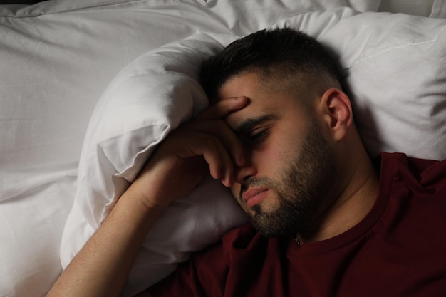 Homme triste allongé sur le lit à la maison vue de haut