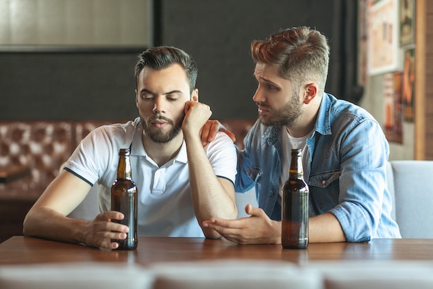 Homme triste buvant de la bière son ami et parlant ensemble