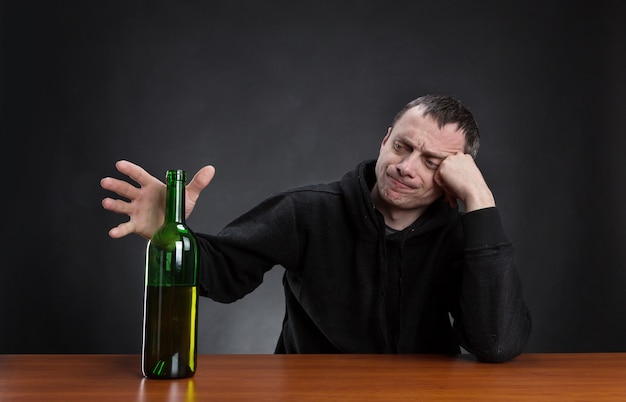 L'homme triste prend une bouteille d'alcool