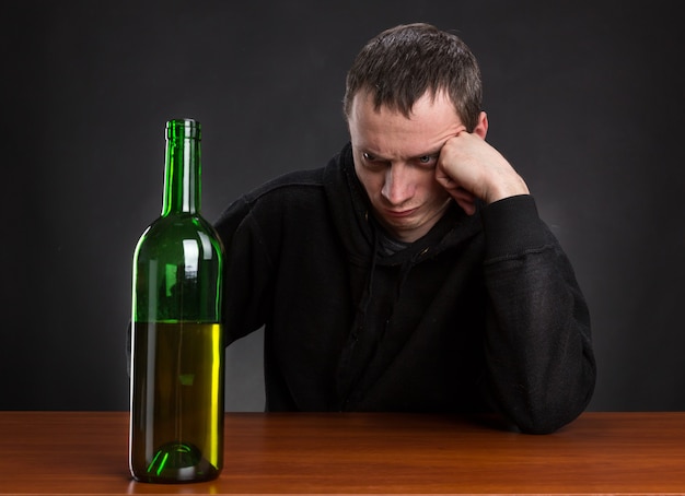 L'homme triste regarde la bouteille de vin