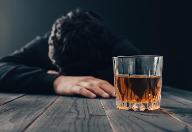 Homme triste avec verre d'alcool sur tablexA