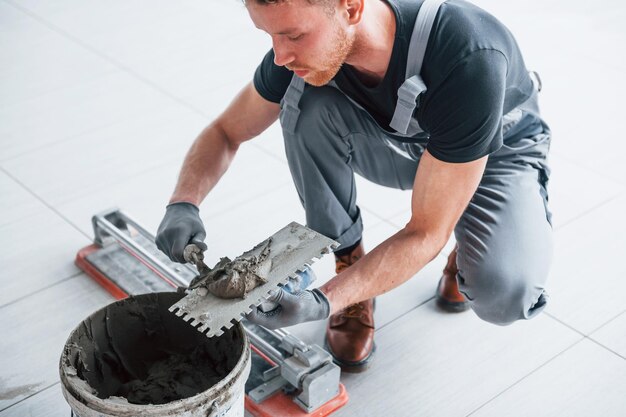 Un homme en uniforme gris travaille avec une assiette à l'intérieur dans un grand bureau moderne pendant la journée