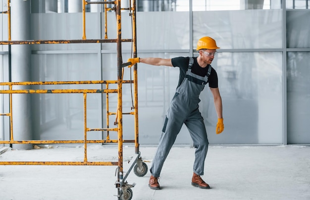 L'homme en uniforme gris travaille avec la construction à l'intérieur dans un grand bureau moderne pendant la journée