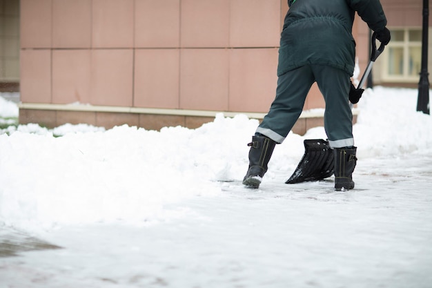 Un homme en uniforme nettoie le trottoir de la neige. Espace libre pour un texte