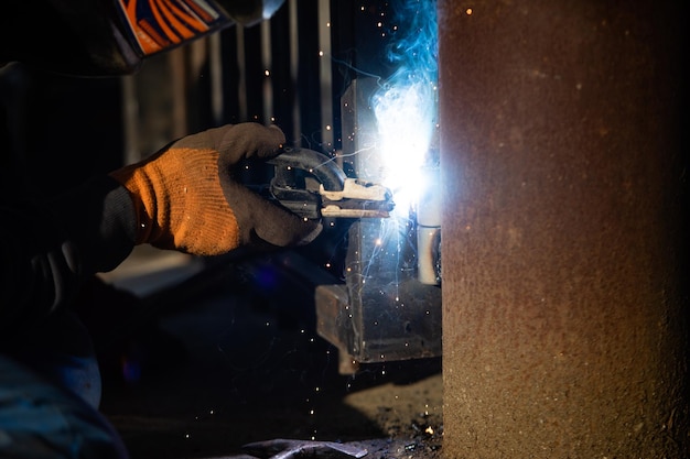 L'homme en uniforme soude un métal à l'usine