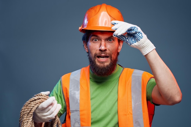 Photo homme en uniforme de travail peinture orange corde dans les mains travail dur vue coupée photo de haute qualité