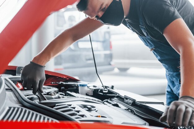 Homme en uniforme travaille avec une automobile cassée Conception du service de voiture