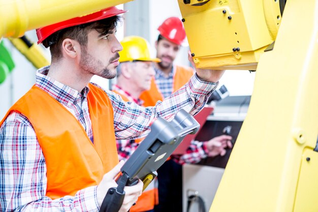 Homme en usine examinant un robot industriel