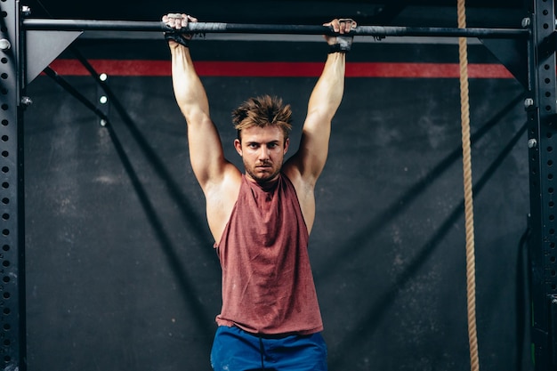 Homme utilisant une barre pour faire des tractions dans une salle de sport