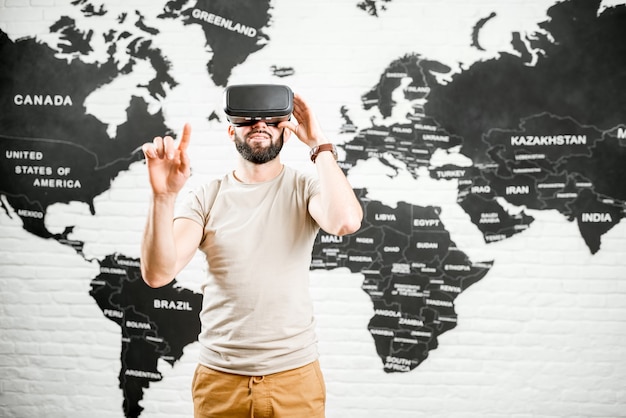 Homme utilisant des lunettes de réalité virtuelle assis à l'intérieur avec une carte du monde en arrière-plan