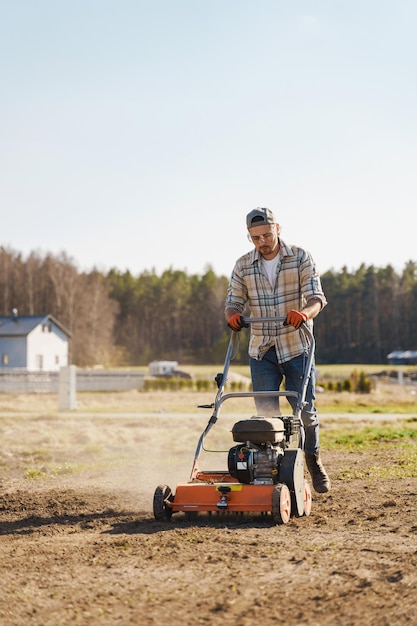 Homme utilisant une machine d'aération pour la scarification et l'aération de la pelouse ou du pré