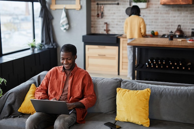 Homme utilisant un ordinateur portable sur un canapé