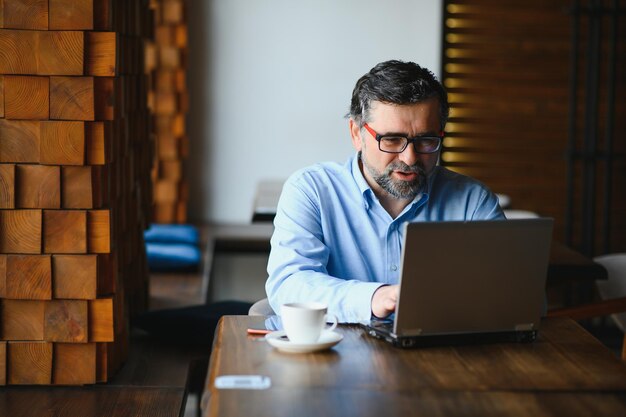 Homme utilisant un ordinateur portable dans un café-bar