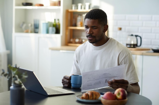 Homme utilisant un ordinateur portable pour travailler en ligne à la maison