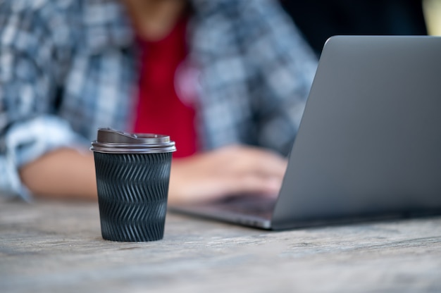 Un homme utilisant un ordinateur portable à son bureau, une tasse de café sur la table.