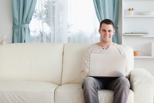 Homme utilisant un ordinateur portable tout en étant assis sur un canapé