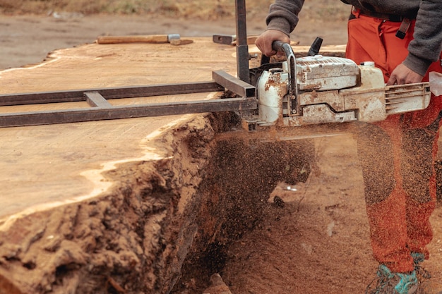 Un homme utilisant une scie circulaire pour couper une souche d'arbre.