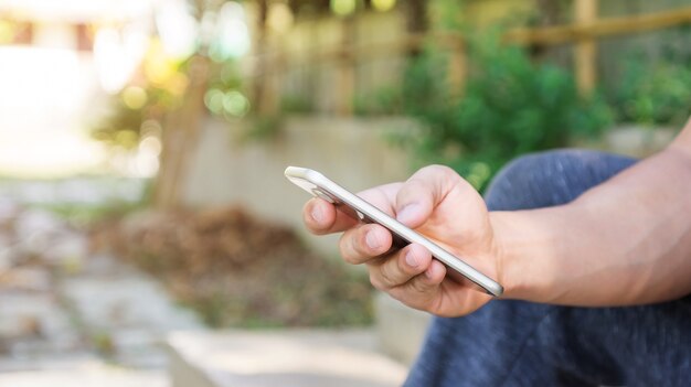 Homme utilisant un smartphone dans un jardin.