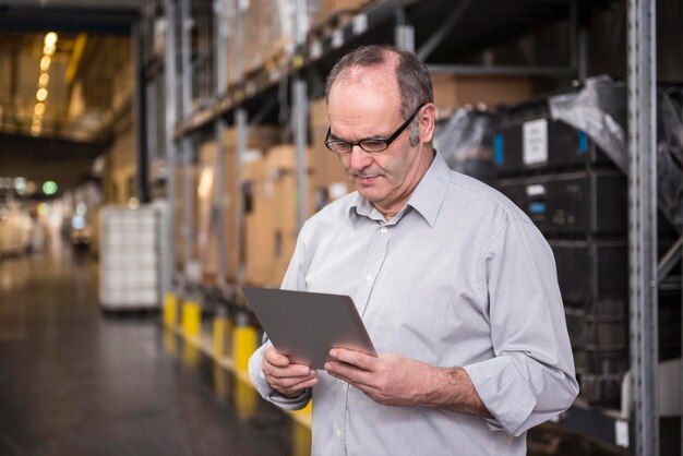 Homme utilisant une tablette dans un entrepôt d'usine