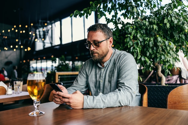 Homme utilisant un téléphone intelligent dans un bar.