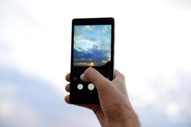 Homme utilisant un téléphone intelligent pour prendre une photo d'un beau ciel