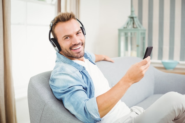 Homme utilisant un téléphone intelligent tout en écoutant de la musique