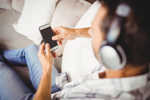 Homme utilisant un téléphone portable tout en écoutant de la musique